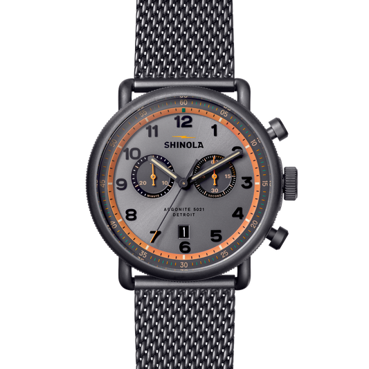 Shinola Apportion 5821 Detroit watch featuring a dark gray dial with orange accents, black bezel, and a black mesh strap, shown on a solid white background.